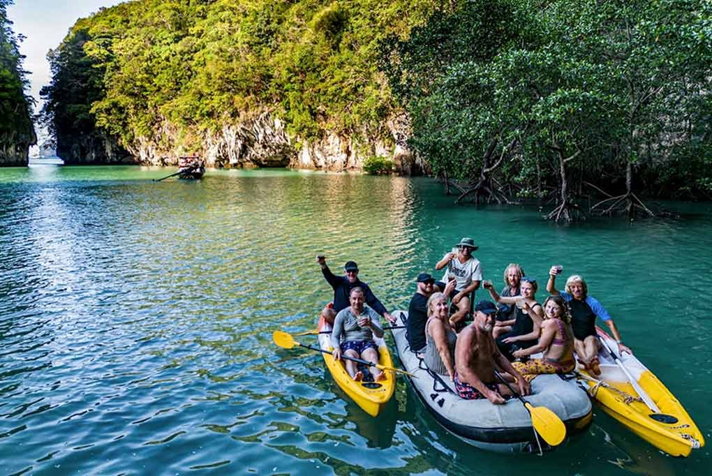 guests raising a glass to the camera from Nyami's 2 kayaks and dinghy within the mangrove hongs of Phang Nga Bay