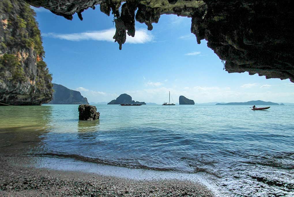 55ft nyami charter catamaran anchored in phang nga bay pictured from within a limestone cave on a deserted beach in Phang Nga Bay