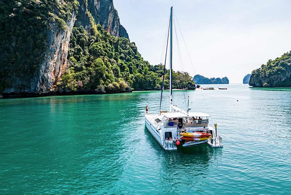 view from the stern of nyami, a 55ft charter catamaran motoring between limestone rock formations and islands in phang nga bay thailand