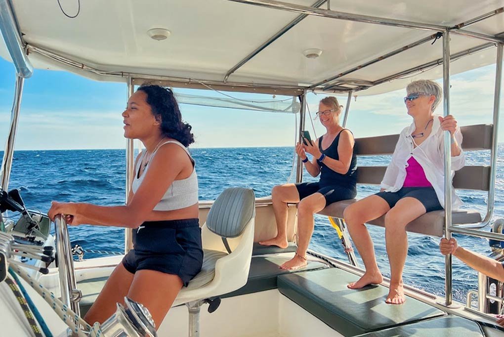 midday sailing from Nyami's wheelhouse with three ladies, one at the helm in the cool breeze out at sea in phang Nga Bay